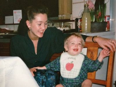 Alexander Vlahos is sitting in a chair as Nicci Vlahos is playing with him.